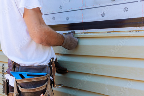 Handyman process installing vinyl PVC siding during construction on facade new home