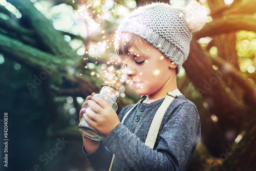 Magic, jar and light outdoor in nature with glow, shine and young child playing in forest. Boy, sparkle and happy in woods as dream with fantasy for unique mystical fairy, folklore and pixie dust