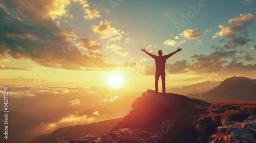 Sunset with a joyful and happy person’s silhouette gazing at the horizon, with mountains, clouds, and the brilliant sun. An epic background for motivational quotes