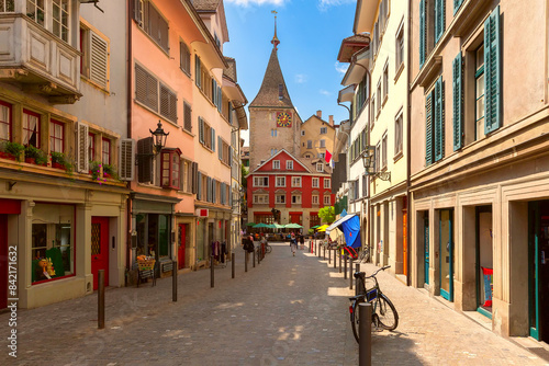 Charming street in old town of Zurich, Switzerland, featuring colorful buildings and clock tower