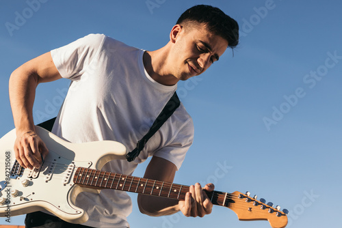 man playing electric guitar on a blue sky background