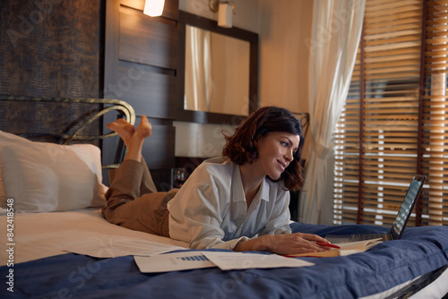 Busy young businesswoman working online from hotel room