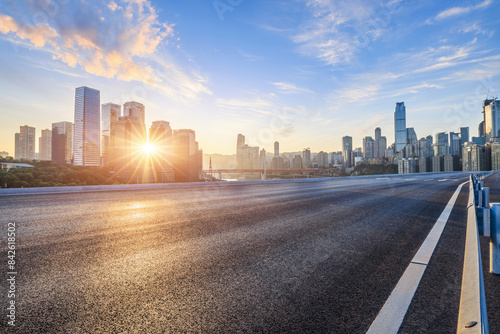 Asphalt road and city skyline with modern buildings in Chongqing at sunrise.