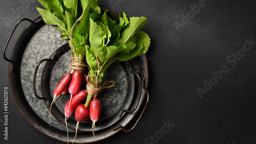 ripe red radishes with green leaves in a metal bowl. Organic food. Close up.