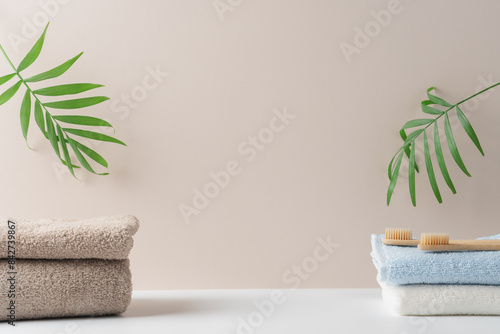 Stack of terry towels on light background with tropical plants. White background for the presentation of cosmetic, medical natural bio products