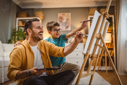 Father teach mentor son to create art at home on easel with brush