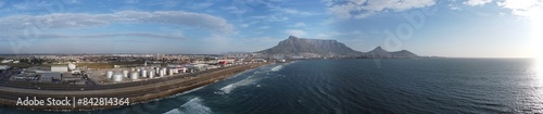 Panoramic photo of coastline close to Cape Town showing Table Mountain and industrial area with railway track.