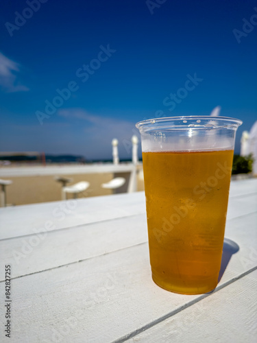 szklanka zimnego piwa stojąca na białym drewnianym stole na plaży w Gdyni