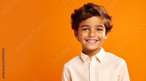 Portrait of a cute happy Hispanic Latino boy child with perfect skin, orange background, banner.