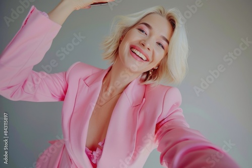 A woman in a pink suit taking a photo of herself with her smartphone