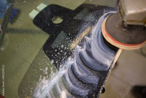 A professional technician expertly polishes glass surfaces in a workshop with precision