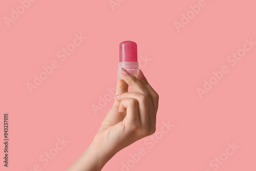 Female hand with crystal deodorant on pink background