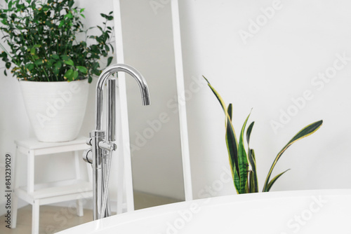 Bathtub with silver tap in light room, closeup
