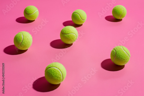 A collection of tennis balls on a pink background