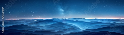 Stunning panoramic view of a mountain range under a starry sky, with a mesmerizing blue hue and a serene, ethereal feel.