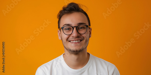 Portrait of a young man with glasses on an orange background 