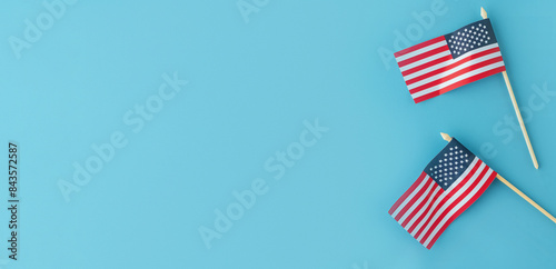 Two small American flags against blue background, flags are positioned in right half of banner, creating large amount of negative space that can be utilized for text or other design elements