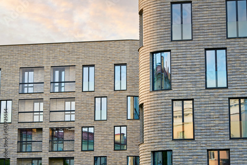 Modern residential building with large windows and clinker brick facade against susnet sky. Clinker brick facade and floor-to-ceiling glass windows