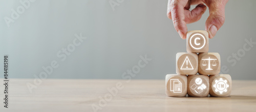 Copyright or patent concept, Hand holding wooden block on desk with copyright icon on virtual screen, Author rights and patented intellectual property, copyleft trademark license.