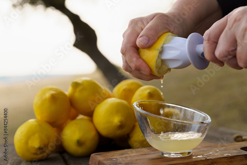 Woman squeezing lemon juice with reamer into glass on table