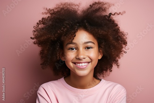 Portrait of a little afro mestizo girl on a pink background in pink clothes.