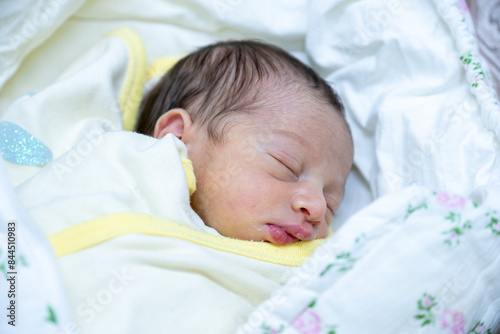 On her first day of life, a newborn baby girl wears a pink hospital ID bracelet on her hand