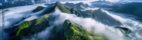 Breathtaking aerial view of lush green mountain peaks covered in mist and clouds, showcasing nature's beauty and serenity.