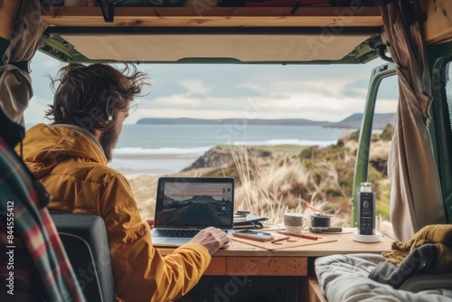 A digital nomad working from a camper van with a laptop on a small desk and an open door revealing a picturesque landscape
