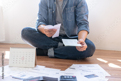 Financial concept, owe asian young man sitting suffer, stressed and confused by calculate expense from invoice credit card bill, no money to pay mortgage or loan. Debt, bankrupt or bankrupt people.