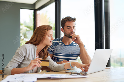 Laptop, couple and credit card at table in morning for online shopping with purchase in house on weekend. Internet, banking and finance with bills, taxes and monthly payments for debt in apartment.