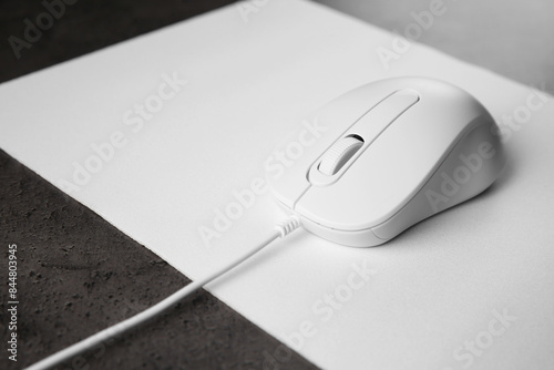 Wired mouse with mousepad on black textured table, closeup