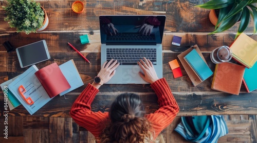 A top-down view of a content creator working on a laptop surrounded by notebooks and creative materials