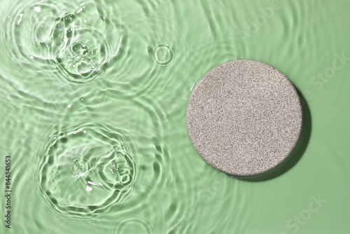 Presentation of product. Stone podium in water on green background, top view. Space for text