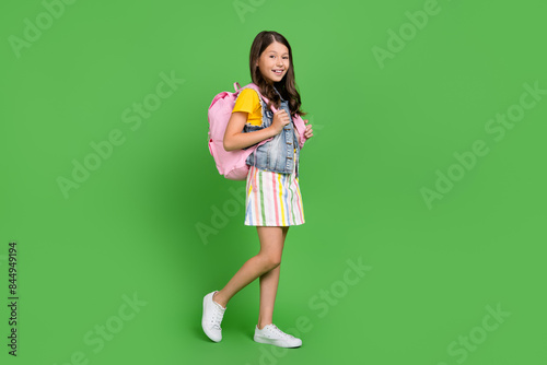 Photo of positive girl kid go walk hold wear backpack isolated green color background