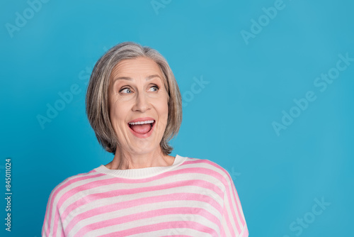 Photo portrait of lovely pensioner lady look excited empty space dressed stylish striped garment isolated on blue color background