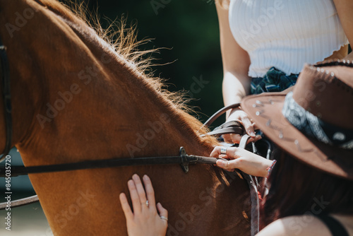 Close-up view of two women handling reins on a horse, focusing on the bond between rider and animal in an outdoor setting.