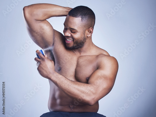 Black man, cologne and spray in studio for beauty, underarm and perfume bottle on blue background. Person, deodorant and armpit for aroma or fresh scent, clean smell and shirtless for fragrance