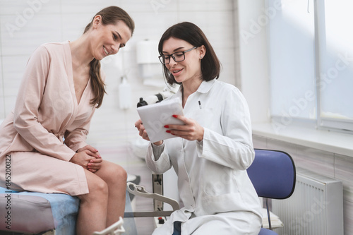 woman doctor look microscope at gynecologist's appointment. Female gynecologist examining patient on chair with equipment. doctor shows test results to patient and explains treatment strategy