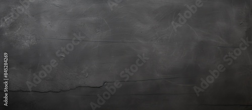 A textured black anthracite grunge stone concrete wall with a blackboard or chalkboard texture serves as a captivating background for a panoramic banner with ample copy space image