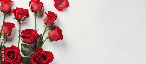 A top view of a white background showcasing gorgeous red roses and buds Ample space is available for adding text The image is presented as a flat lay