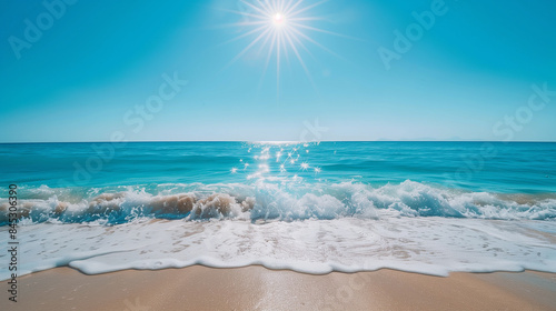 Sunny beachscape with gentle waves lapping the shore under a clear blue sky.