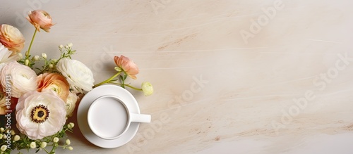 Cup of coffee and flowers composition with ranunculus and gypsophila on beige marble table Copyspace
