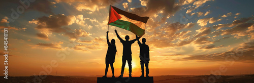 Dramatic silhouette of people raising a Palestinian flag against a vivid sunset sky, symbolizing unity and freedom