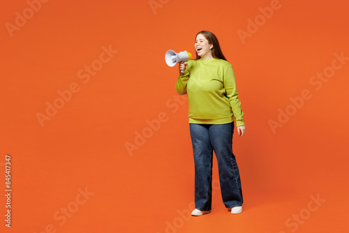 Full body young ginger fat chubby plus size woman wear green sweatshirt casual clothes hold megaphone scream announces discounts sale Hurry up isolated on red orange background. Body positive concept.