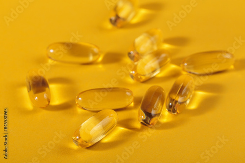 Diet, nutrition, healthy eating concept. Close up of oil filled yellow softgels capsules of food supplements on yellow background.