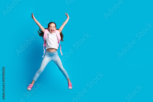 Photo of charming positive girl wear white t-shirt rucksack jumping high empty space isolated blue color background