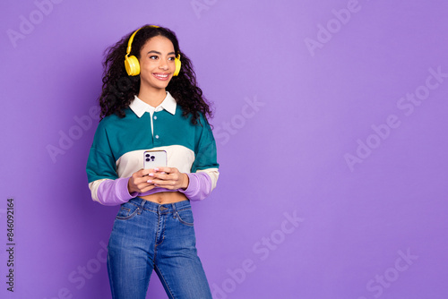 Photo of nice young girl headphones smart phone look empty space wear shirt isolated on violet color background