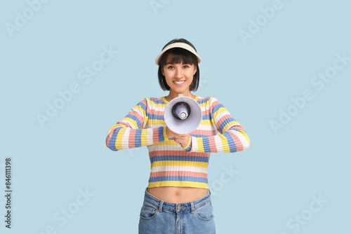 Young woman with megaphone on blue background