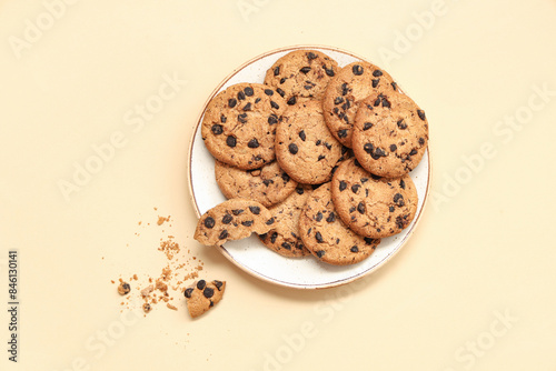 Plate of sweet cookies with chocolate chips on beige background