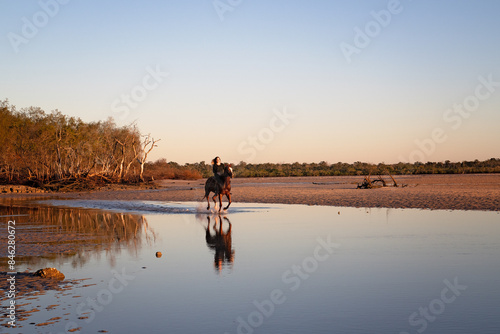 woman riding horse on beach at sunrise dawn, Woodgate Beach, Queensland, Australia